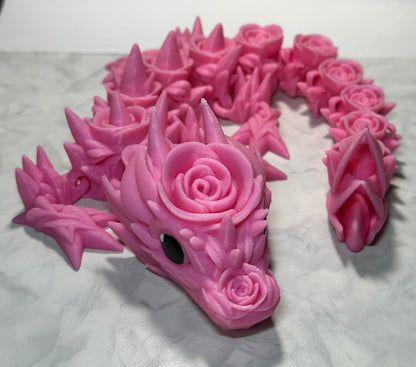 A pink 3D printed dragon figurine with a rose pattern.